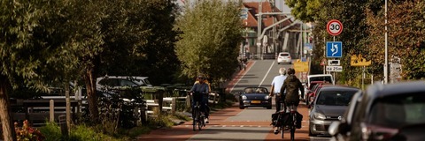 Fietsers en auto's rijden op de Brugweg richting de Hefbrug van Waddinxveen.