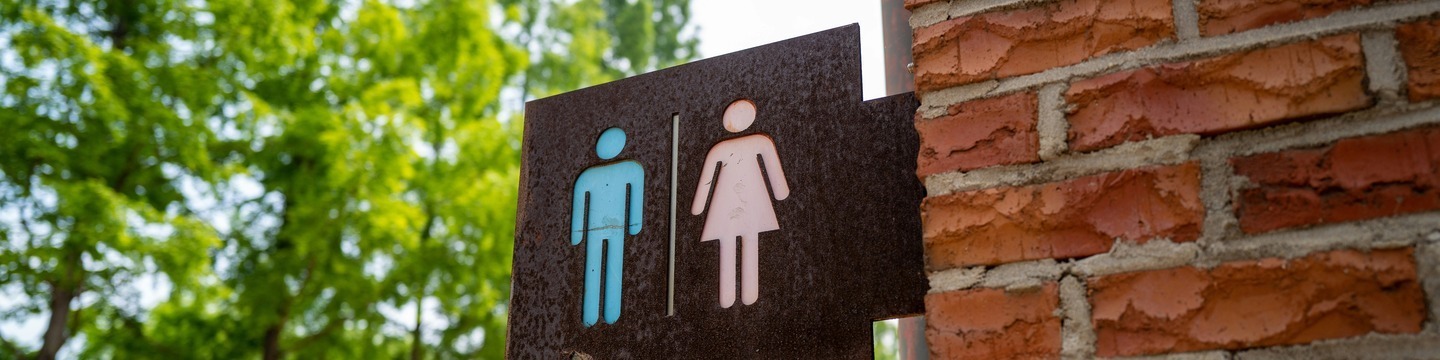 een blauwe afbeelding van een man en een roze afbeelding van een vrouw op een bord aan de muur